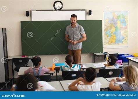Male Teacher Teaching In Classroom Of Elementary School Stock Image
