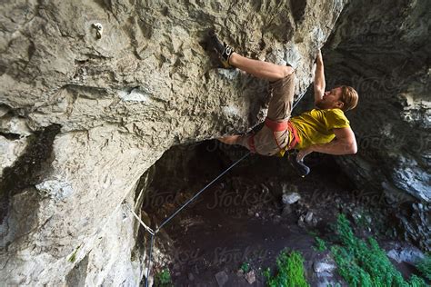 Man Climbing Overhanging Route Above A Cave By Stocksy Contributor