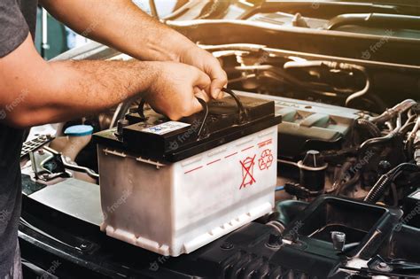 Premium Photo A Auto Mechanic Carries A Replacement Car Battery For