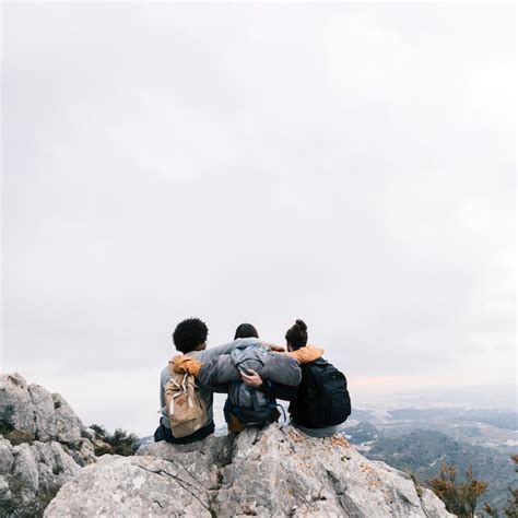 Three Friends Sitting On The Top Of Mountain Enjoying The View Free Photo