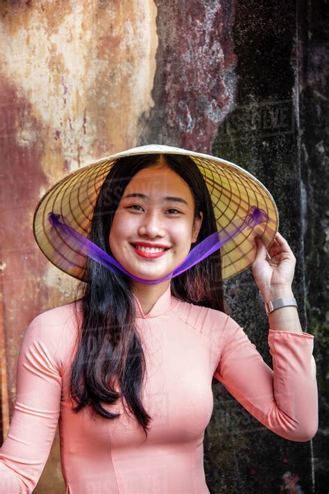 A Young Vietnamese Woman In A Traditional Ao Dai Dress And Conical Hat