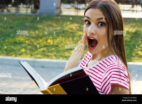 Surprised Young Girl Reading A Book Outside Stock Photo Alamy