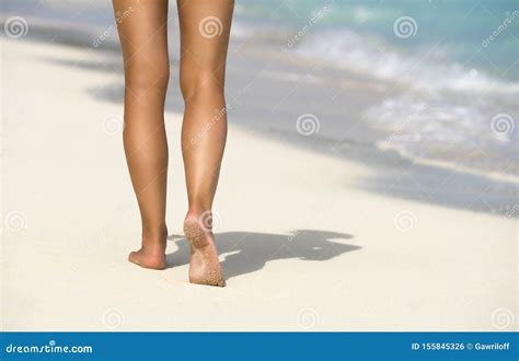 Close Up Of Female Legs In The Blue Water On The Tropical Beach