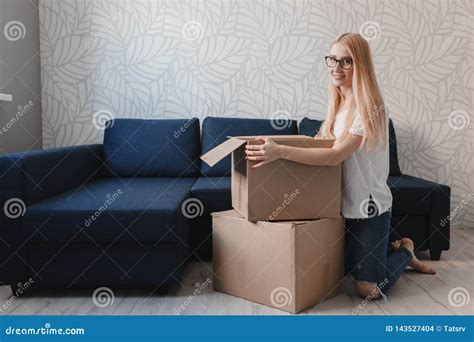 Young Woman Moving Into New Apartment Holding Cardboard Boxes With