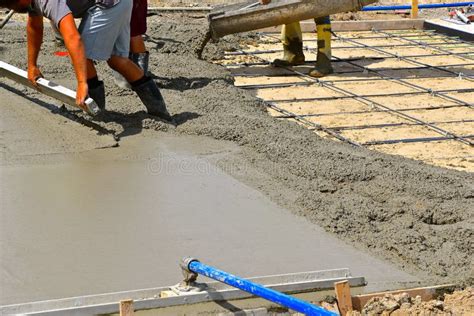 A Team Of Concrete Workers Lay Wet Mud Over A New Driveway Site Stock
