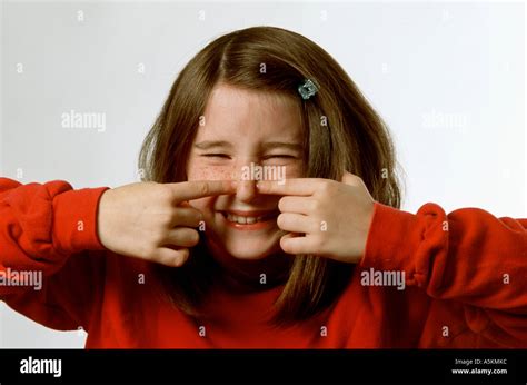 A Young Girl Is Holding Her Fingers Up To Her Nose Humorously As Though