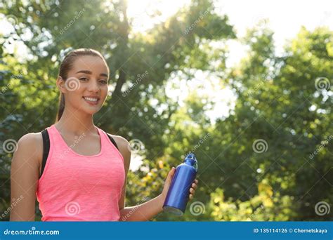 Young Sporty Woman With Water Bottle In Park On Sunny Day Stock Photo