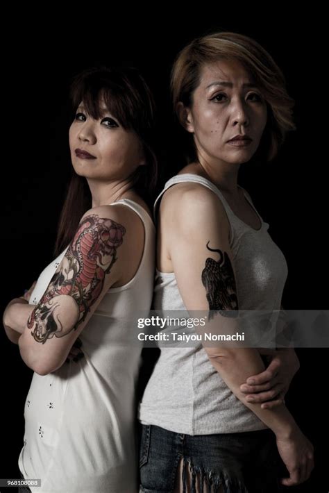 portrait of two tattooed japanese women taken with a dramatic black background high res stock