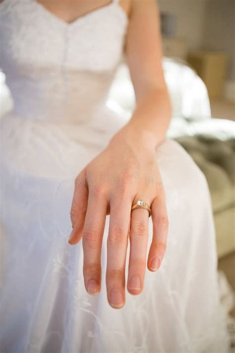 Midsection Of Bride Showing Wedding Ring While Sitting On Bed Stock