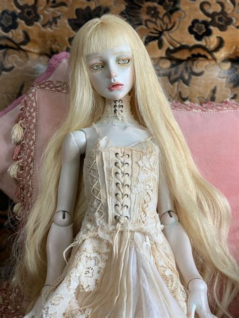 A Doll With Long Blonde Hair Sitting On A Couch