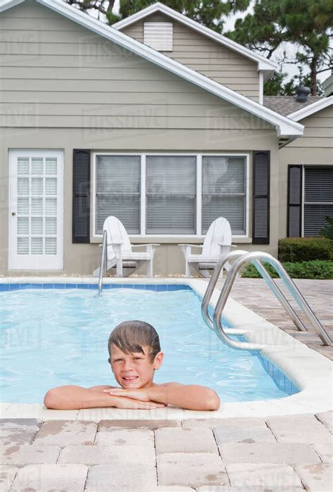 Boy Leaning On Edge Of Swimming Pool Stock Photo Dissolve