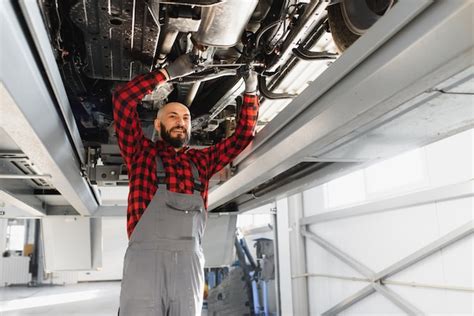Premium Photo Auto Mechanic Working Underneath A Lifted Car