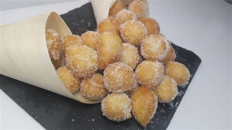 Some Sugared Donuts Are In A Cone On A Black Plate With White Icing