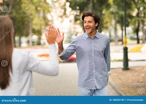 Man Waving Hello Gesture Meeting Female Friend Walking Outdoors Stock