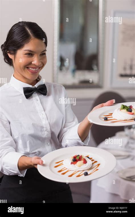 Pretty Waitress Holding Two Dessert Plates In A Fancy Restaurant Stock