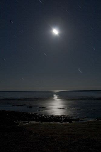 The Moon Shines Brightly Over The Ocean At Night