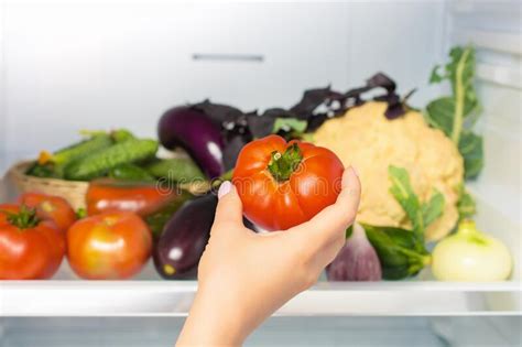Woman`s Hand Picks Up Tomato From The Refrigerator Shelf Healthy Food