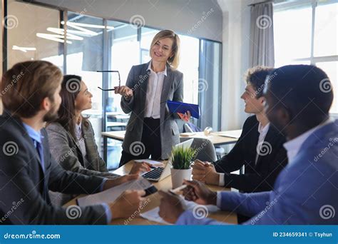 Female Boss Addressing Meeting Around Boardroom Table Stock Image