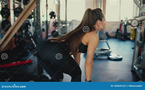 Young Beautiful Brunette Girl Wih Long Hair In The Gym Doing Exercises On The Squat With A Bar