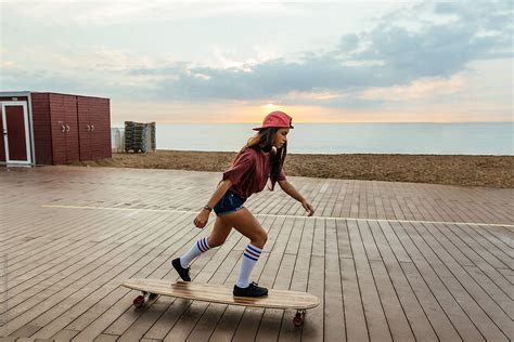 Trendy Girl Riding A Longboard By The Beach At Sunrise Stocksy United