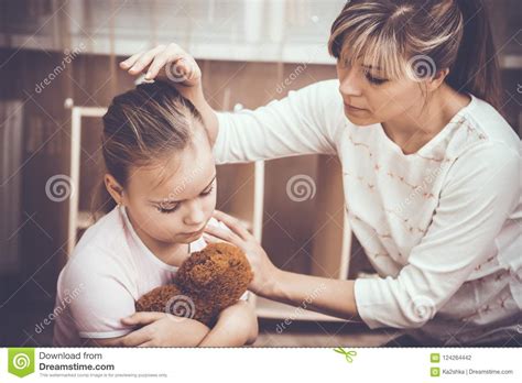 Little Sulky Girl Being Sad And Her Mother Consoling Her Stock Photo