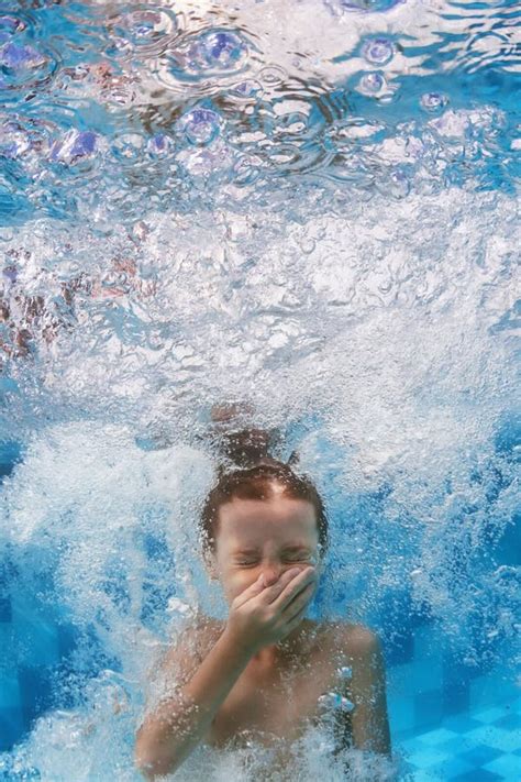 Swimming Child Jumps Underwater In The Blue Pool With Splashes Stock
