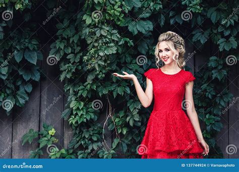 Attractive Young Blonde In Red Dress Holds Copy Space On Palm Against