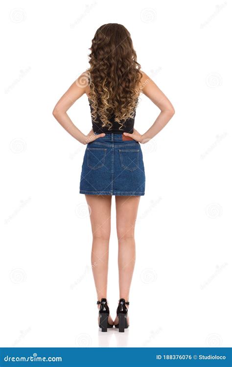 Rear View Of Young Beautiful Woman In Jeans Mini Skirt Black Top And