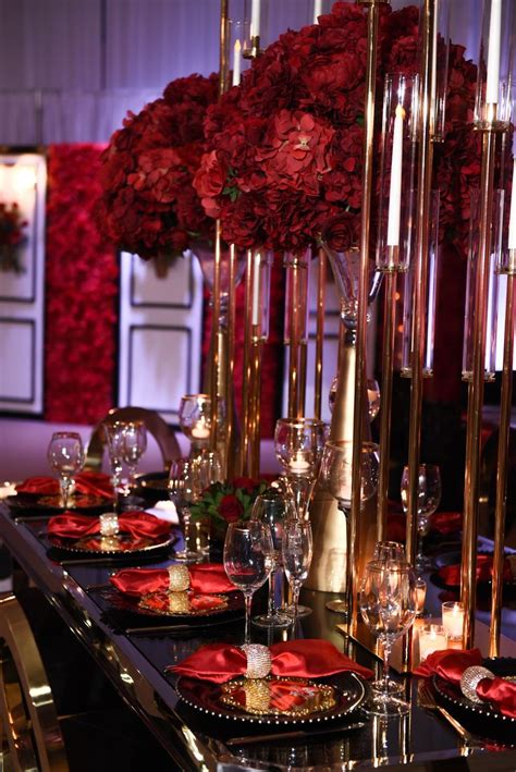 The Table Is Set With Red Flowers And Gold Candlesticks For An Elegant