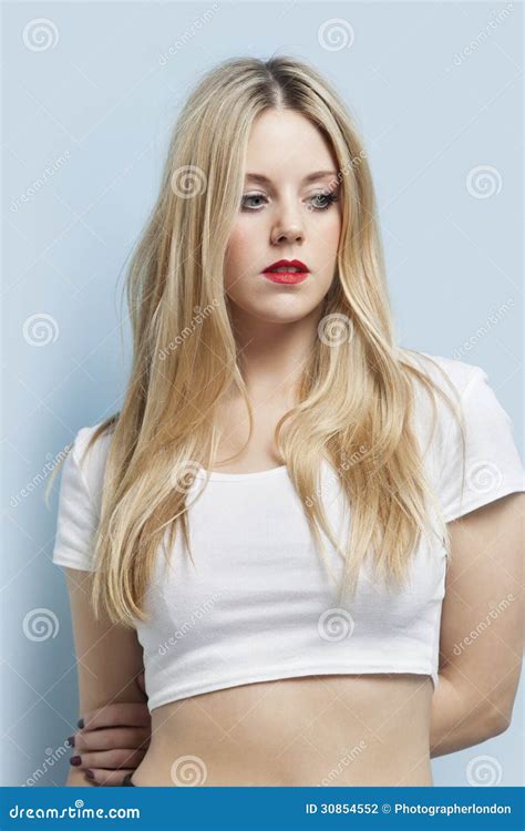 belle femme blonde avec les lèvres rouges regardant vers le bas sur le fond bleu clair
