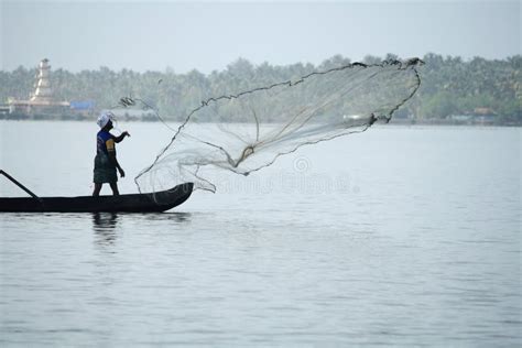 Fishermen In A Boat Catch Fish By Throwing Net In To The Backwaters