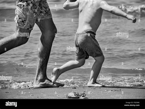Father And Son Running On The Beach During Summer Vacation Stock Photo
