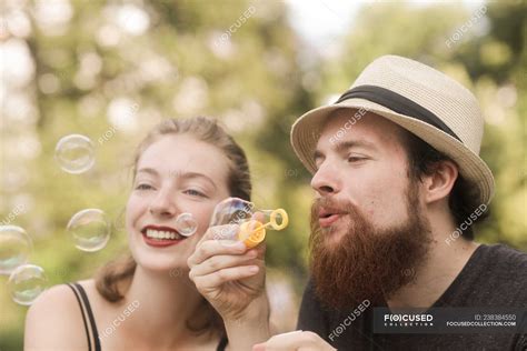 Couple Sitting In A Park Holding A Bubble Wand Blowing Bubbles — Recreational Pursuit City