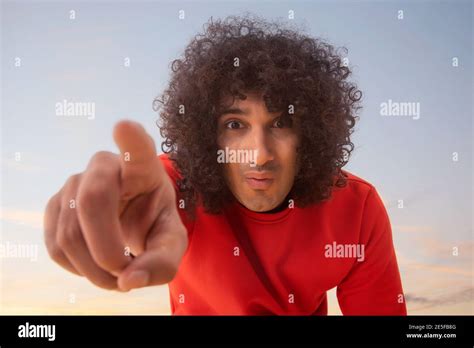 A Young Man With Curly Hair Pointing Finger Towards Camera Stock Photo