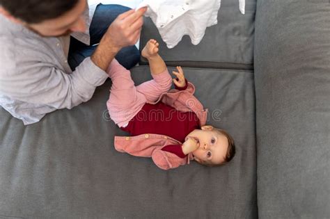 Father With Toddler Daughter Taking Care Of His Baby Changing Clothes