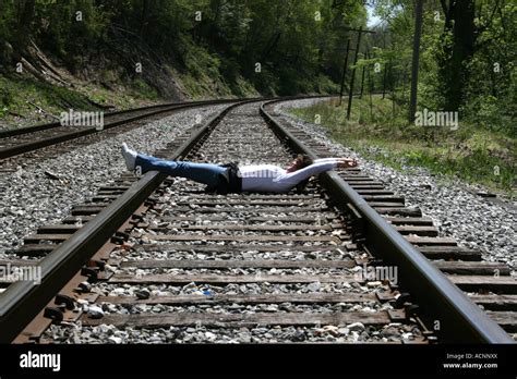 Woman Lying On Railroad Tracks With Hands And Feet Bound Stock Photo