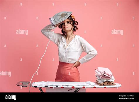 tired housewife ironing clothes on ironing board attractive woman with hair curlers on her head