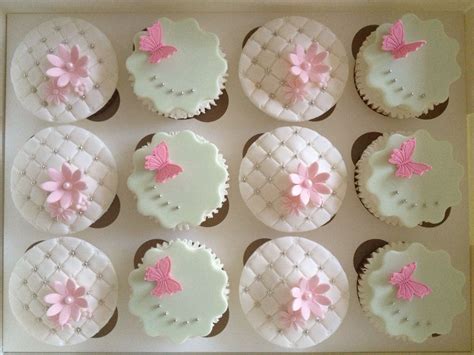 Twelve Cupcakes Decorated With Pink And White Icing In A Box On Top Of