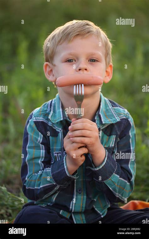 Little Boy On A Picnic Eats Sausage Stock Photo Alamy