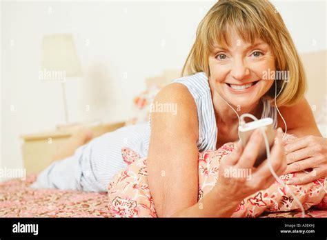Portrait Of A Mature Woman Lying On The Bed Listening To An Mp3 Player
