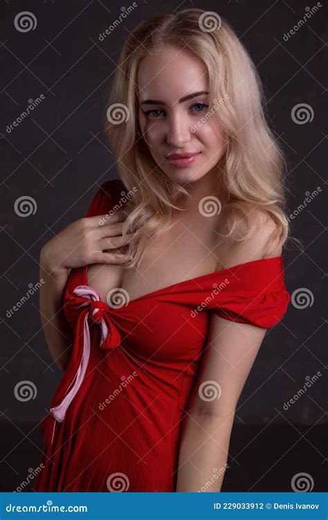Beautiful Blonde In A Red Dress On A Black Background Stock Photo