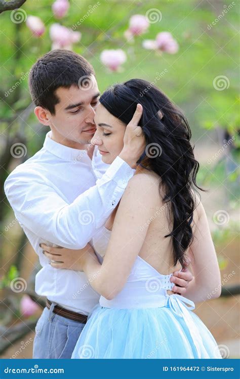 Young Happy Female Person And Brunette Man Hugging Near Blooming Tree