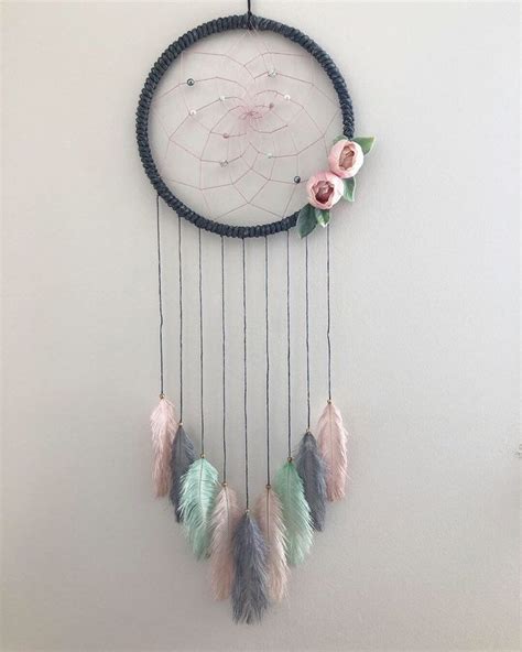 A Dream Catcher With Flowers And Feathers Hanging On The Wall