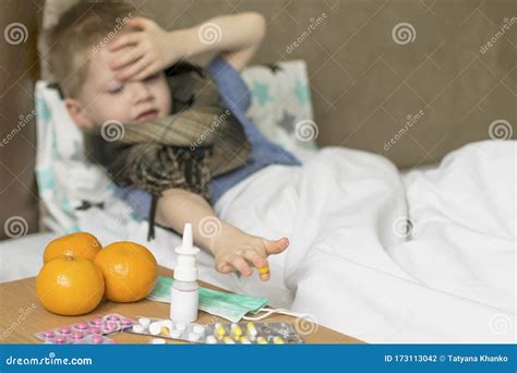 A Sick Sad Child With A Temperature And A Headache Lies In Bed Next To