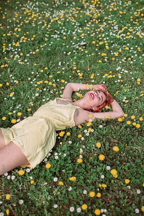 A Woman Laying On The Ground In A Field Full Of Daisies And Dandelions