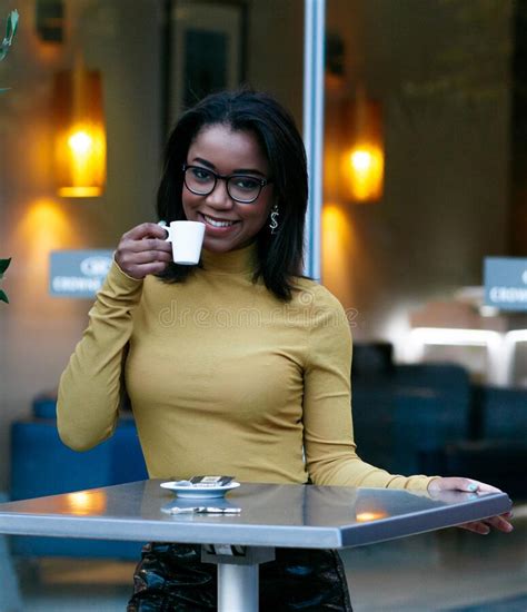 Black Female Standing Next To The Table With A Cup Of Coffee Stock