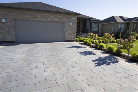 A Driveway With Landscaping In Front Of It And Two Garages On The Other