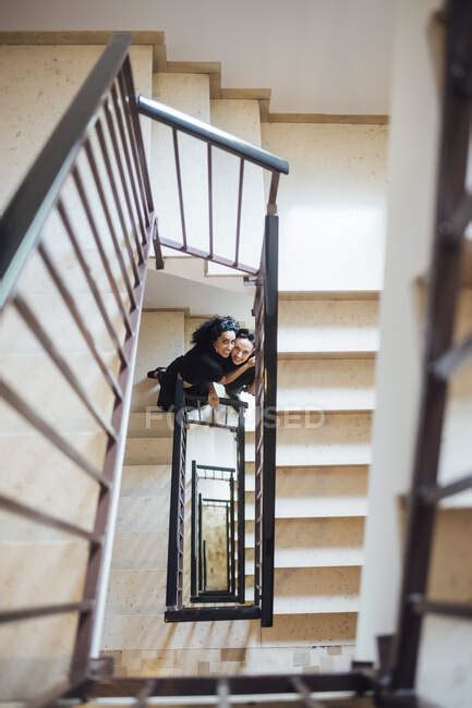 Smiling Lesbian Couple Moving Down On Staircase — Individuality Casual