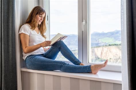 Premium Photo Young Woman Reading Sitting In The Window Of Her House
