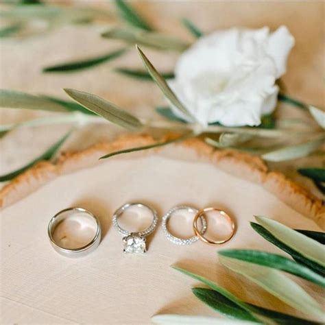 Three Wedding Rings Sitting On Top Of A Table Next To A White Flower